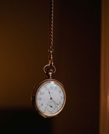 A pocket watch hanging from a chain in a dark room